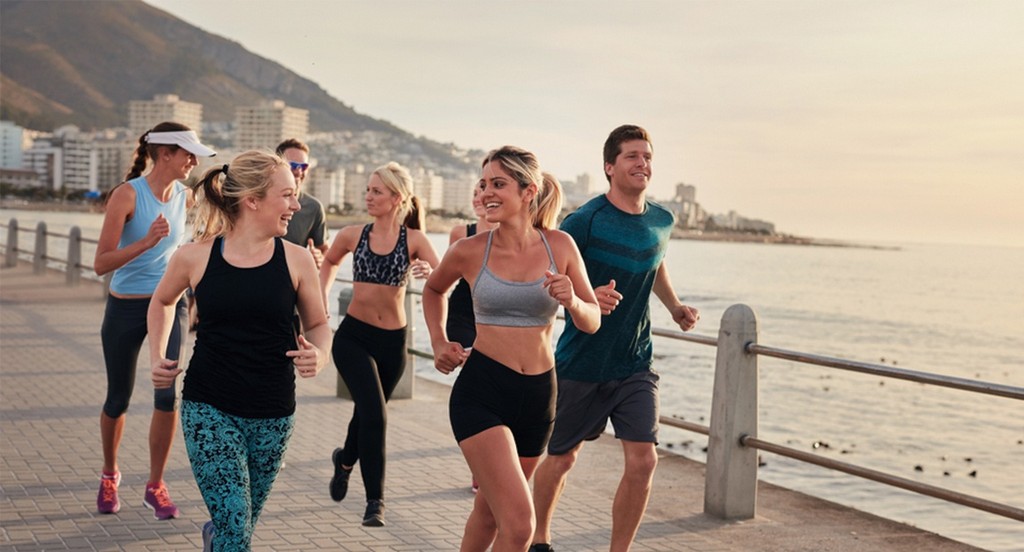People running on a boardwalk next to the ocean